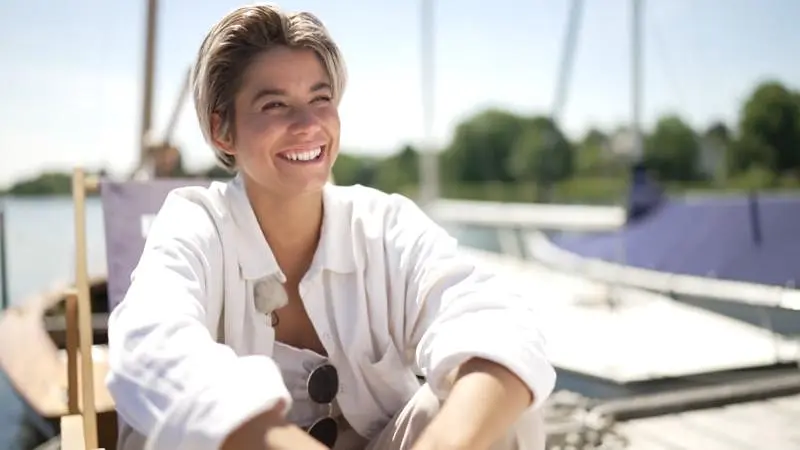 A woman smiles brightly by the boat in Princess Charming Season 2.